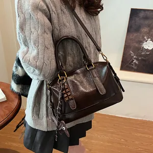 Vintage brown glossy crossbody bag with chocolate charm and gold hardware on grey sweater