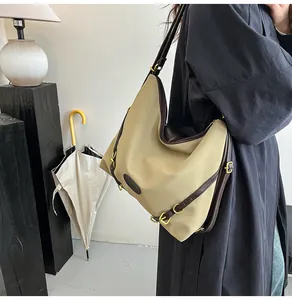 Detail showing high-capacity khaki tote bag with dark brown leather straps and gold hardware