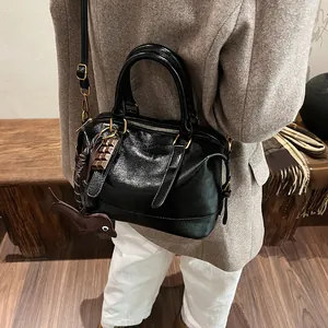 Retro black leather Boston bag with gold hardware and charms on brown wool coat