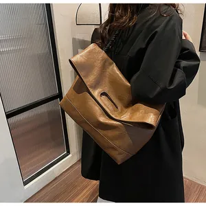 Détail d'un grand cabas en cuir marron souple avec poignée découpée et texture