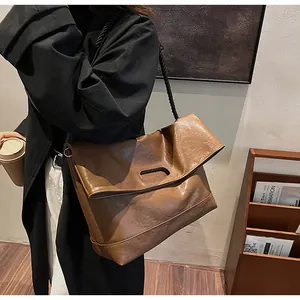 Vue latérale d'un grand sac cabas en cuir souple marron porté par un mannequin chic