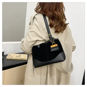Detailed back view of a black suede patchwork bucket bag with gold chain charm on a model