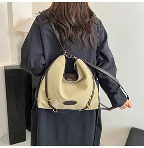 Detail of a beige tote bag showing leather trim and vintage gold ring accents on a strap