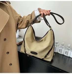Detail of khaki nylon tote bag featuring dark brown leather handles and golden metal buckle