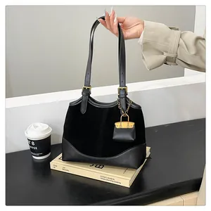 Detail of black suede and smooth leather tote bag featuring gold hardware and mini pouch charm