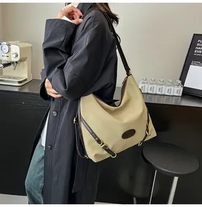 Detail of a large beige tote bag with brown leather straps and gold metal hardware