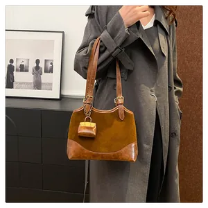 Detail of vintage brown suede bucket bag featuring leather trim and a mini pouch charm