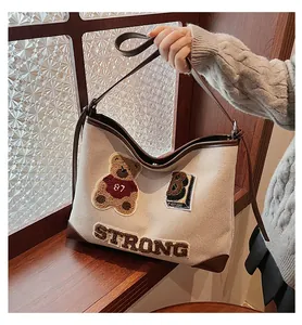 Detail of canvas tote bag featuring teddy bear embroidery and premium leather accents