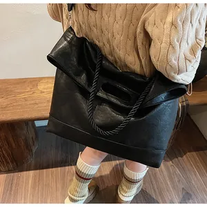 Détail du grand sac cabas en cuir souple noir avec anses en corde tressée et design pliable