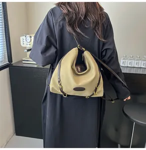 Detail of khaki tote bag with brown leather trim and golden buckle on model