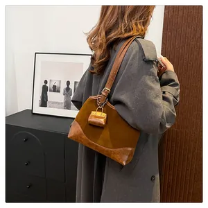 Close-up of retro brown suede bucket bag with leather trim and mini pouch detail