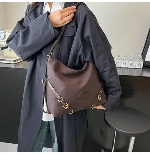 Detail of dark brown leather hobo bag with gold buckle and embossed logo patch