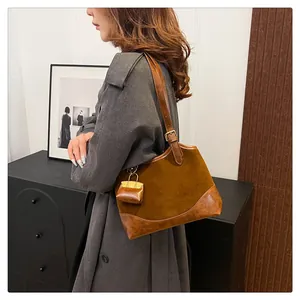 Detail of a brown leather and suede bucket bag with a mini matching pouch on the strap