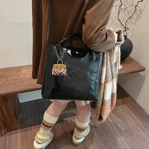 Modieuze zwarte glanzende tote bag met luipaardprint hanger en metalen ketting