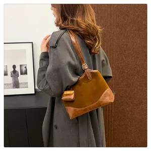 Detail of vintage brown suede shoulder bag with leather trim and matching charm pendant