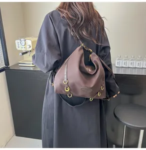Detail of a large brown pleated tote bag with golden hardware on a shoulder strap