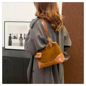 Detail of retro brown suede bucket bag texture and small charm on a shoulder strap