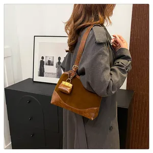 Brown vintage bucket bag shoulder view with mini pouch charm on suede texture