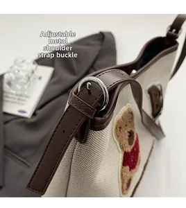 Detail of adjustable leather strap with silver metal buckle on a canvas tote bag