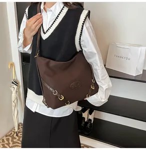 Detail of dark brown large canvas tote bag with adjustable strap worn as a crossbody bag