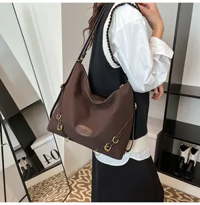 Close-up of deep brown tote bag featuring golden metal rings and logo leather patch