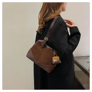 Close-up of brown suede bucket bag with leather trim and orange charm accessory