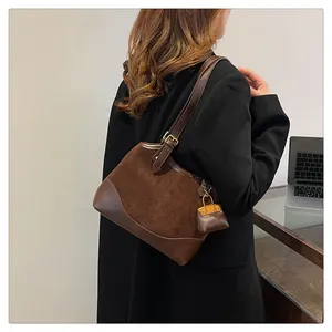 Detailed side view of dark brown bucket bag with adjustable strap and mini charm