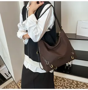 Detail view of large dark brown pleated tote bag with golden rings and logo patch