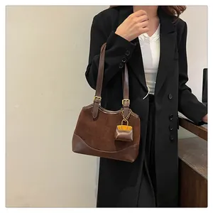 Detail of dark brown suede bucket bag with leather stitching and adjustable straps