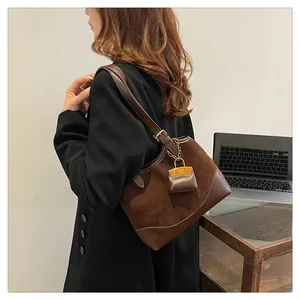 Detail of vintage brown suede shoulder bag with leather trim and decorative charm