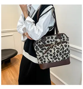 Detail of leopard print tote bag with brown leather handles and golden metal buckle