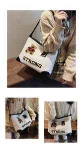 Detail of canvas tote bag featuring teddy bear embroidery and black leather trim