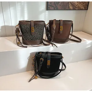 Détails des sacs seaux en motif léopard et daim avec fermoir doré et pampille