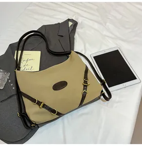 Top view of large khaki tote bag with brown leather straps on a white fabric surface