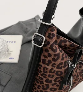 Detalle del bolso con estampado de leopardo, asa de cuero negro y hebilla de plata