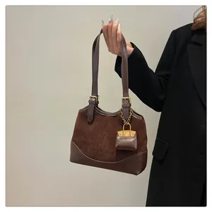 Detail of dark brown bucket bag featuring metal buckles and a mini bag charm accessory