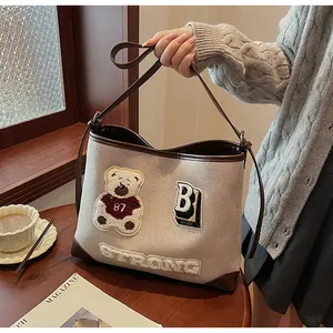 Detail of canvas tote bag with bear embroidery and textured STRONG letter patches