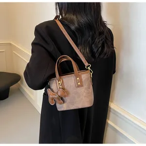 Detailaufnahme der Vintage-Beuteltasche mit Goldbeschlägen und Bärenanhänger