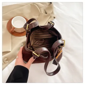 Close-up of bucket bag interior featuring striped lining, zipper pocket, and leather texture