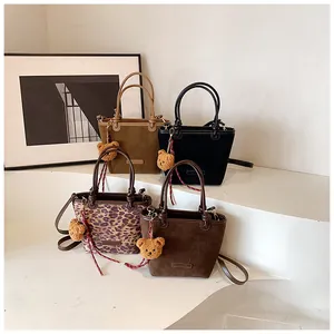 Dettaglio di quattro borse a secchiello in stampa leopardata, kaki, marrone e nero con orso
