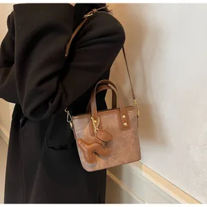 Details der braunen Vintage-Tasche mit Wildleder-Textur und kleinem Hundeanhänger