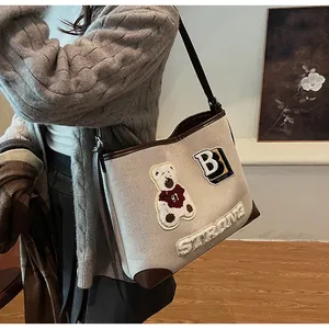 Detail of canvas tote bag featuring bear patch and white fuzzy STRONG letter embroidery