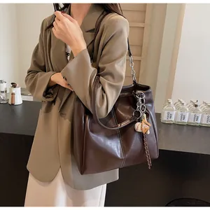 Detalle de bolso tote marrón oscuro con costuras blancas en contraste y correa de cadena