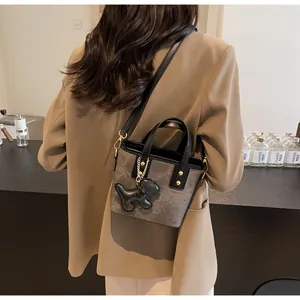 Details der Mini-Retro-Beuteltasche mit schwarzem Lederbesatz und süßem Hundeanhänger