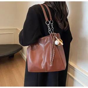 Bolso tote marrón de piel sintética con costuras blancas y colgante de béisbol