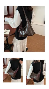 Macro detail of deep brown glossy hobo bag with vintage plaid tassel pendant accessory