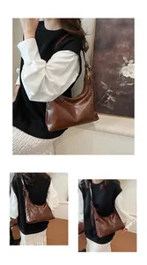 Detail of a brown vintage hobo bag featuring polished leather texture and woven tassel charm