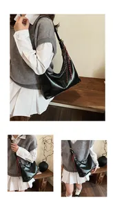 Detail view of a black matte hobo bag featuring a decorative woven tassel and slim strap