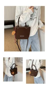 Dettaglio di una borsa a secchiello in camoscio marrone con ciondolo a forma di orsetto