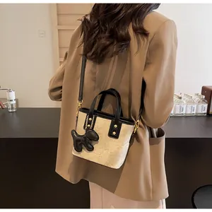 Detailansicht der Eimer-Tasche mit Kontrastnähten, Riemen und kleinem Welpenanhänger